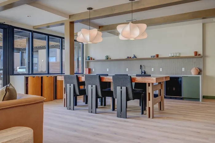 Elegant open-plan dining area with a stylish wooden table, chic chairs, modern pendant lighting, and expansive windows for natural light.