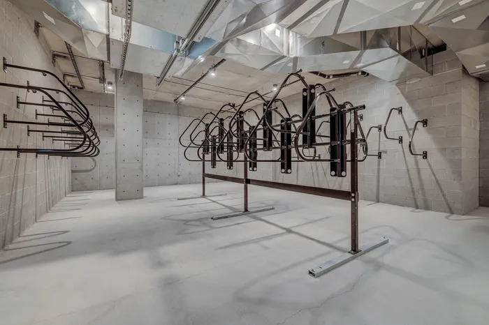 Modern and spacious secure bicycle storage area with industrial design and ample bike racks.