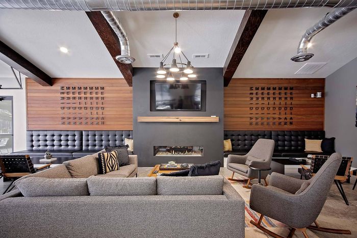 Modern living room with sleek furniture, stylish wood paneling, and a chic fireplace, perfect for relaxation and entertainment.
