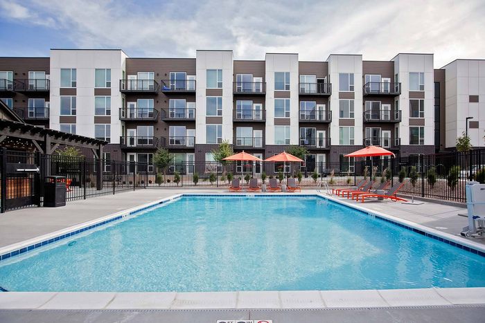 Luxury apartment complex with modern architecture featuring a refreshing swimming pool and vibrant poolside lounges.