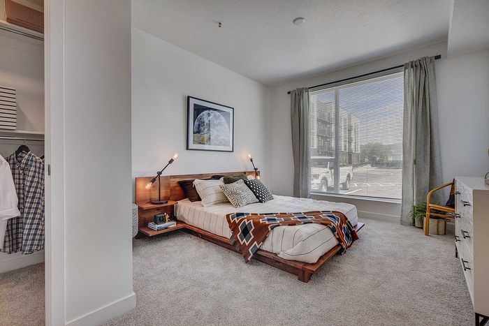 Contemporary bedroom with large window, stylish decor, and cozy atmosphere, perfect for relaxation.