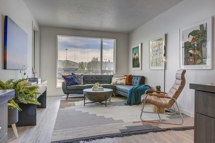 Stylish living room featuring a cozy sectional sofa, modern decor, and large windows with scenic city views.