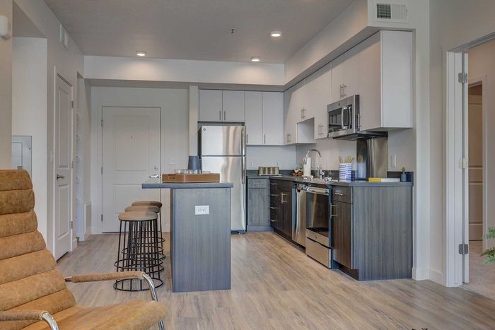 Modern open-concept kitchen with sleek appliances, stylish island seating, and elegant wood flooring.