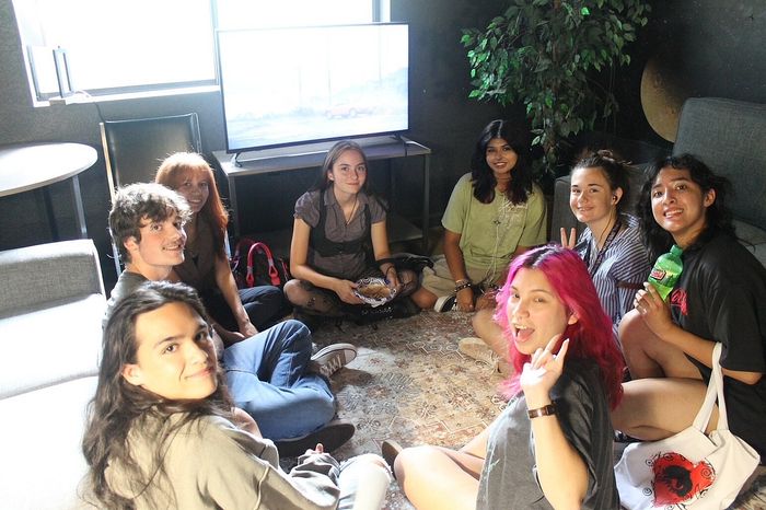 Vibrant gathering of young people enjoying a cozy living space with a modern TV setup, plush seating, and natural light.