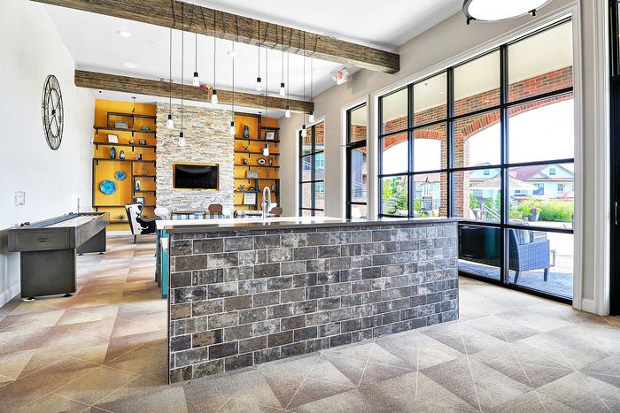 Chic and inviting communal space featuring a stylish brick island, modern pendant lights, and ample natural light from large windows.
