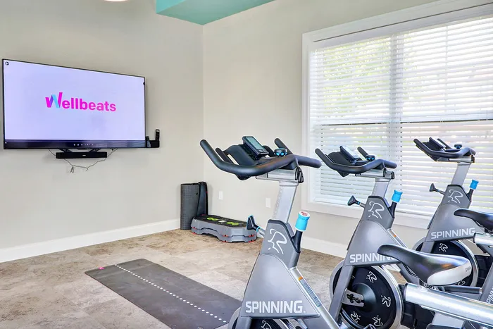 Modern fitness room featuring spinning bikes and a large screen for interactive workouts.