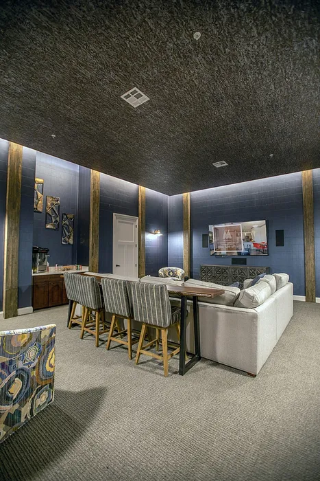 Elegant home theater room with comfortable seating, large wall-mounted TV, and stylish blue walls with artistic decor.