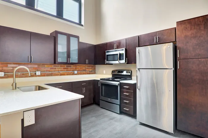 Modern kitchen with sleek stainless steel appliances, dark wood cabinets, and elegant white countertops.