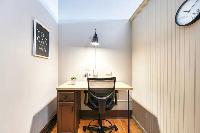 Cozy and stylish home office nook featuring a wooden desk with a sleek chair, enhanced by a motivational wall art and ambient lighting.