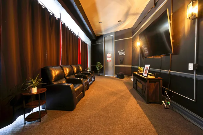 Luxurious home theater room with plush leather seating, ambient lighting, and a large flat-screen TV.