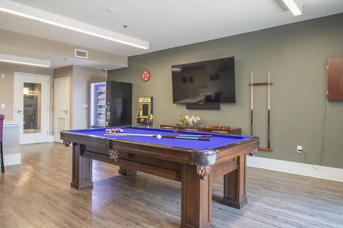 Modern game room with a sleek pool table, large flat-screen TV, and convenient snack vending machine, perfect for entertainment and relaxation.