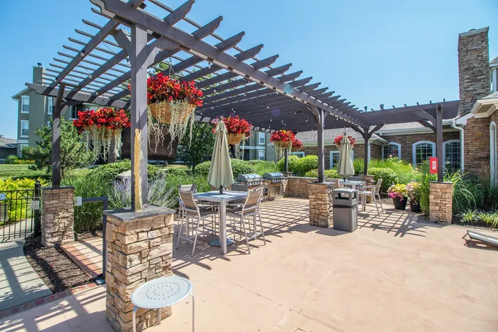 Charming outdoor patio with pergola, elegant seating, and vibrant hanging flowers, ideal for entertaining.
