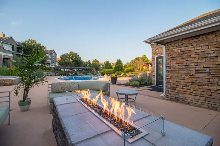 Luxurious outdoor area featuring a cozy fire pit, modern seating, and a sparkling pool with a serene garden backdrop.