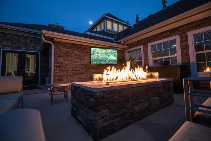 Charming outdoor patio with a cozy stone fire pit and ambient evening lighting, perfect for relaxing gatherings.