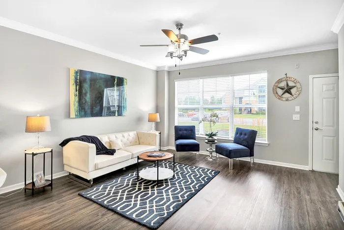 Bright and inviting living room with elegant decor, featuring a plush white sofa, stylish blue chairs, modern art, and abundant natural light.
