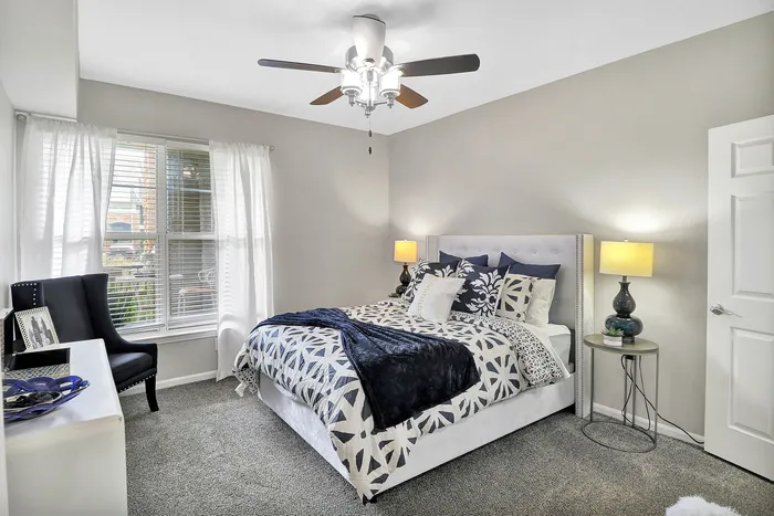 Bright and inviting bedroom featuring a plush bed with elegant bedding, a modern ceiling fan, and ambient lighting, perfect for relaxation.