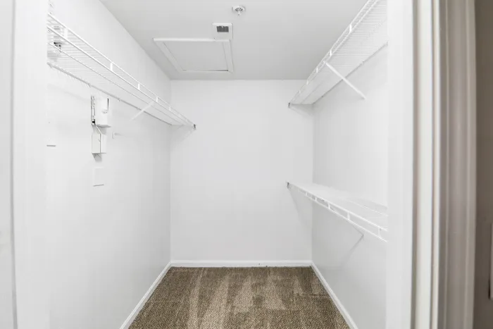 Spacious walk-in closet with clean white shelving, perfect for organizing and maximizing storage space.