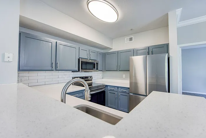 Sleek modern kitchen with stylish grey cabinets, stainless steel appliances, and elegant subway tile backsplash.