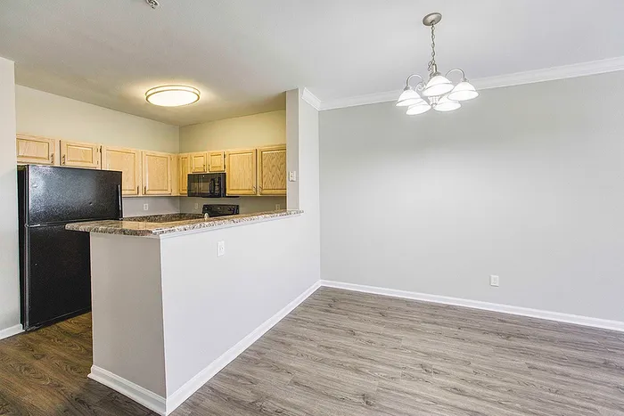 Modern apartment with open kitchen design, featuring chic light fixtures, elegant cabinetry, and sleek wood flooring.