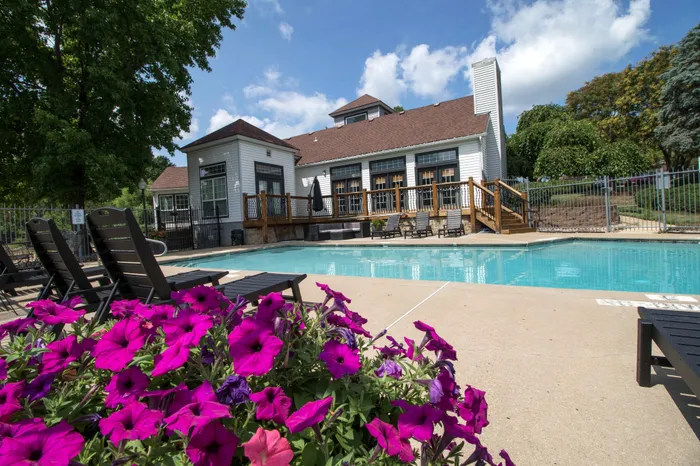 Inviting outdoor pool area with vibrant flowers, cozy lounge chairs, and charming architecture, perfect for relaxation and leisure.