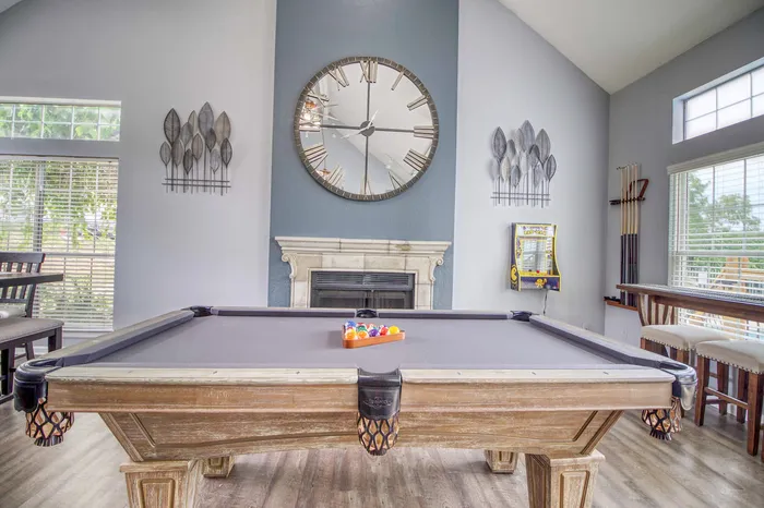 Chic recreation room with a classic pool table, elegant fireplace, and modern decor accents.