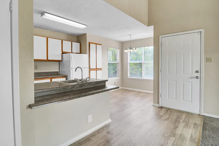 Inviting apartment with a bright kitchen featuring modern cabinets and a cozy dining area with large windows.