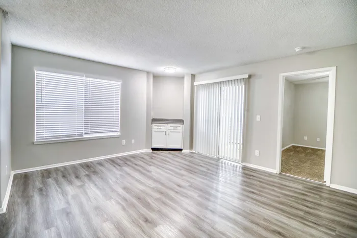 Bright and modern living space featuring sleek wood flooring and abundant natural light from large windows and sliding glass doors.