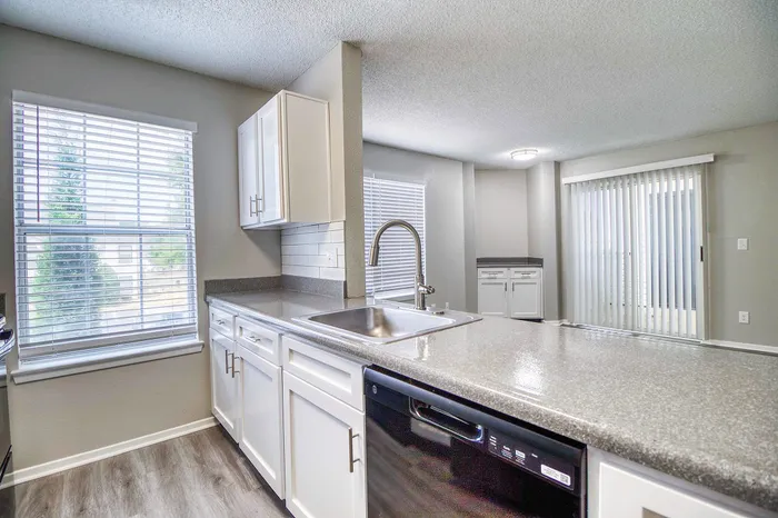 Modern kitchen featuring glossy countertops, sleek white cabinets, and abundant natural light.