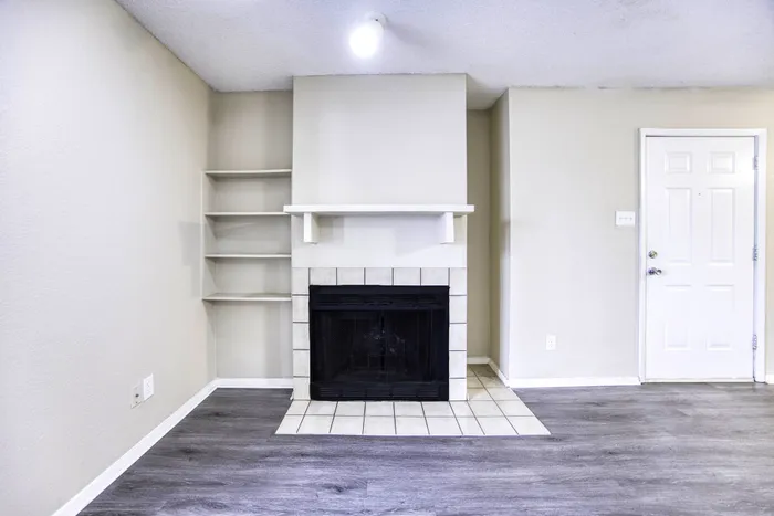 Charming living room with elegant tile fireplace, built-in shelving, and sleek wood flooring.