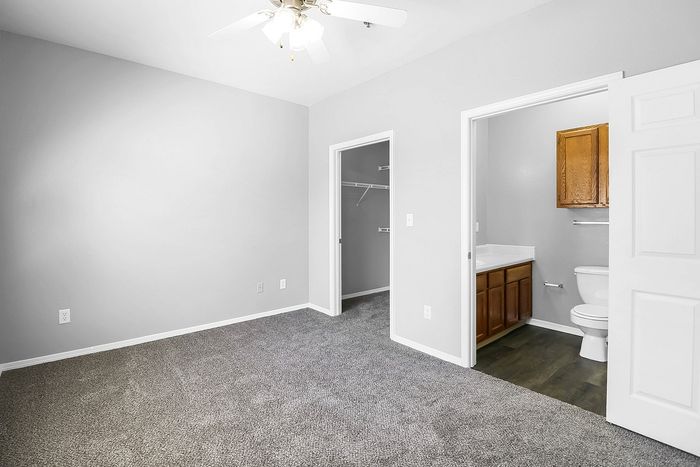Bright bedroom with plush carpet, ceiling fan, and convenient en-suite bathroom and walk-in closet.