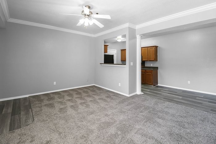 Inviting living space with plush carpeting and a view into the elegant, tile-floored kitchen featuring warm wooden cabinetry.