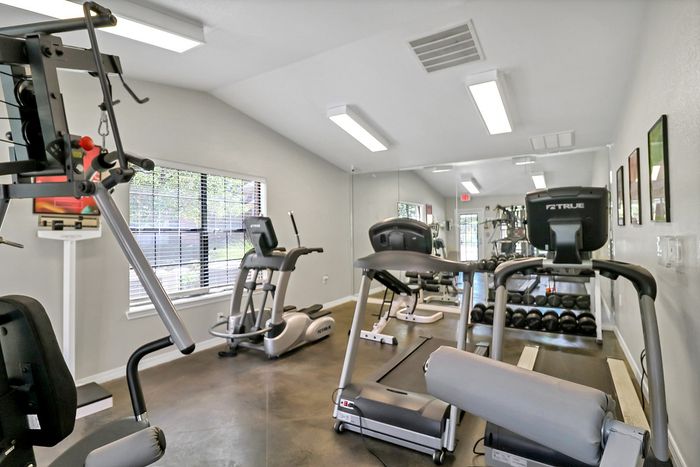 Modern fitness center featuring state-of-the-art equipment, including treadmills, weight machines, and free weights, in a bright and airy space.