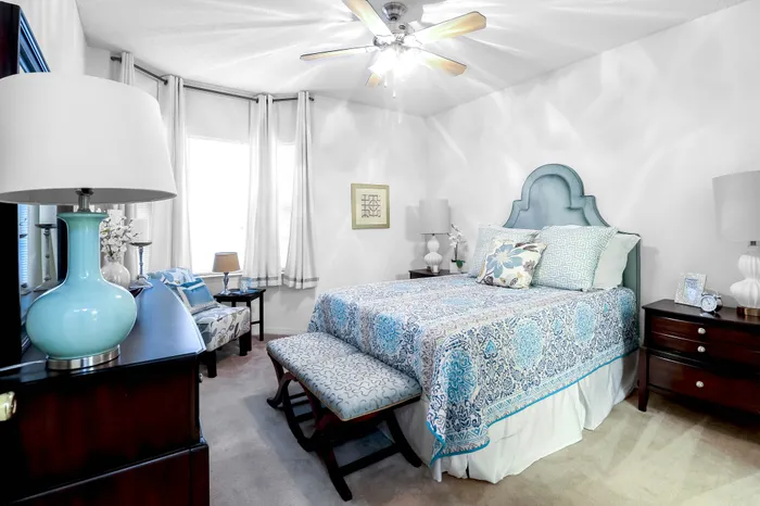 Elegant bedroom with blue accents featuring a plush bed, modern decor, and ample natural light.