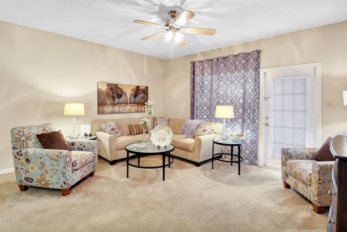 Cozy living room with plush sofas, floral armchairs, elegant decor, and soft lighting, perfect for relaxation and entertaining.