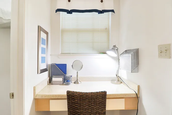Cozy corner workspace with natural light, featuring a sleek desk, modern lamp, and woven chair ideal for productivity.