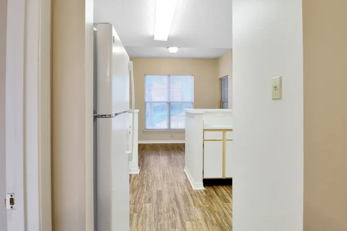 Bright and inviting kitchen area with modern white appliances, elegant hardwood floors, and ample natural light streaming through large windows.