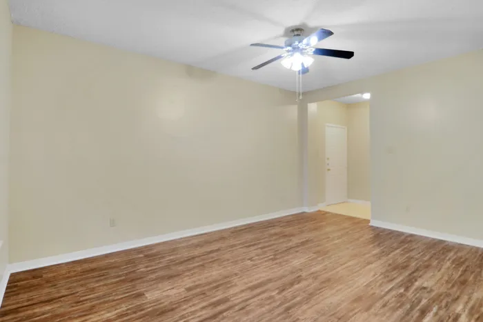 Inviting living space with elegant wood floors and a modern ceiling fan, highlighted by soft beige walls and recessed lighting.