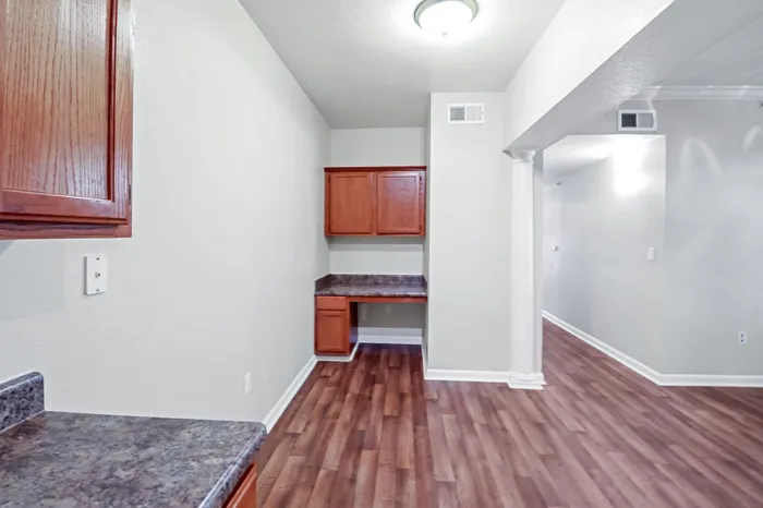 Bright apartment interior featuring elegant wood flooring, sleek countertops, and ample cabinetry for stylish living.