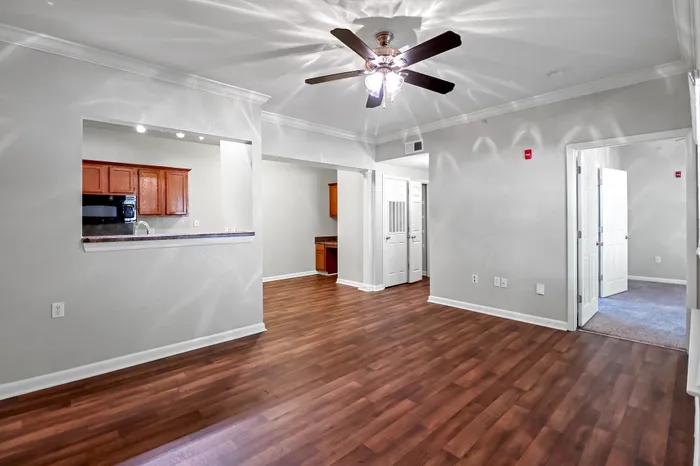 Bright and inviting living area with beautiful hardwood floors, ceiling fan, and modern kitchen pass-through.