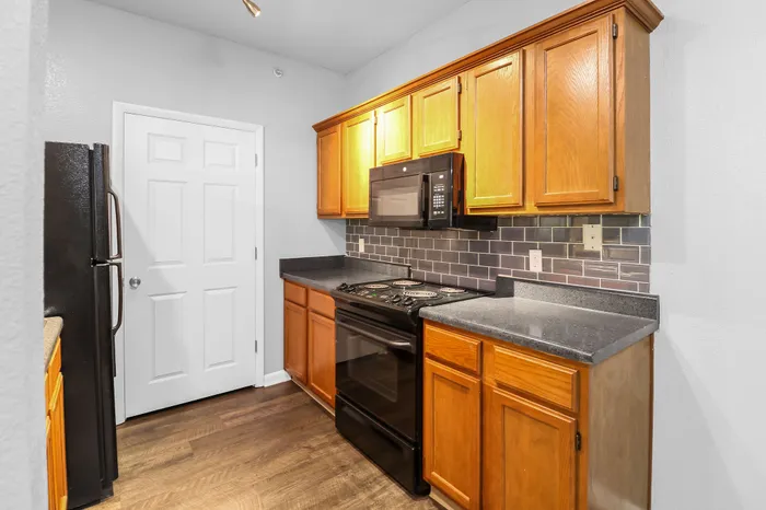 Charming kitchen with warm wood cabinets, sleek black appliances, and elegant tile backsplash.