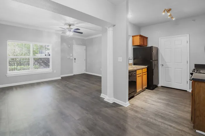 Bright modern apartment showcasing an open-concept living area with sleek hardwood floors, recessed lighting, and a compact kitchen featuring wood cabinetry and elegant finishes.