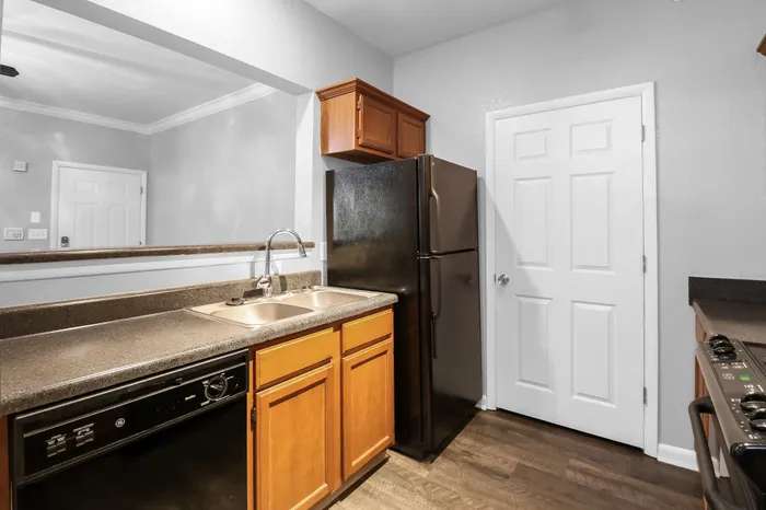 Contemporary kitchen with sleek dark countertops, double sink, black appliances, and elegant wooden cabinetry.