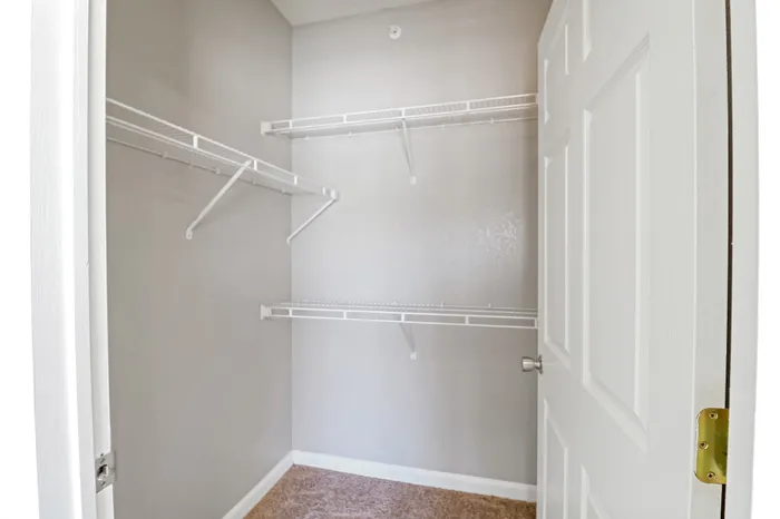 Spacious walk-in closet with ample shelving and neutral decor, perfect for organized storage.