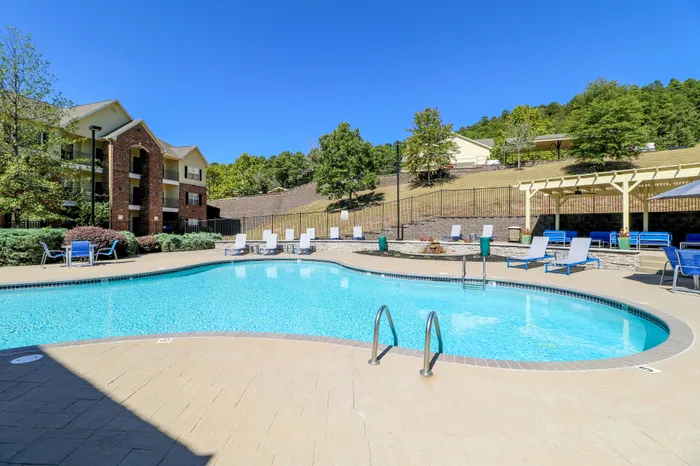 Inviting outdoor swimming pool with lounging area, surrounded by lush greenery and scenic hillside views.