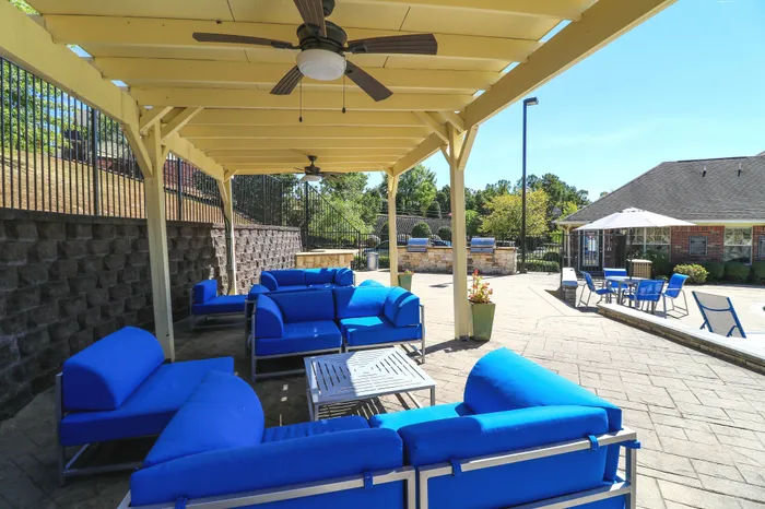 Chic outdoor lounge with vibrant blue seating under a stylish pergola, perfect for relaxation. Features a sunny patio and cozy gathering areas.