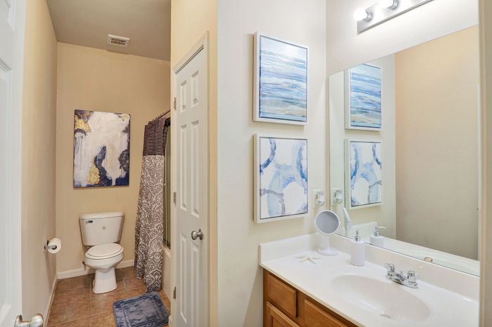 Bright and stylish bathroom featuring modern artwork, elegant lighting, and a pristine vanity.