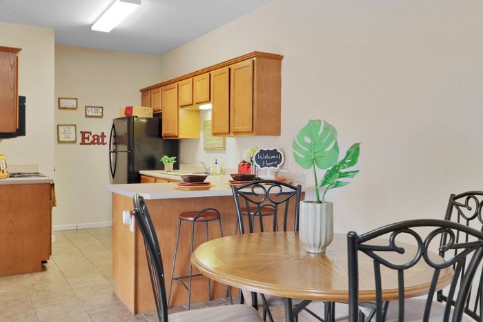 Charming kitchen and dining area featuring warm wooden cabinets, sleek black appliances, and a cozy breakfast bar with stool seating.