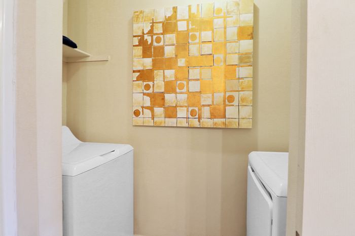 Chic laundry area with modern appliances and stylish abstract artwork for a vibrant touch.