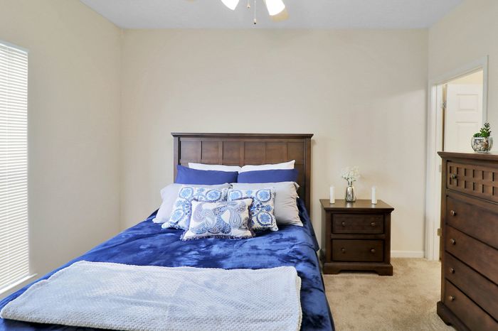 Inviting bedroom with plush blue bedding and elegant wooden furniture, enhanced by soft natural light.