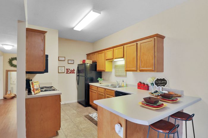 Inviting kitchen with warm wooden cabinets, modern black appliances, and stylish breakfast bar seating.